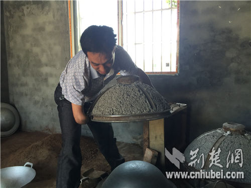 张德春移开模具，取出制作好的铁锅