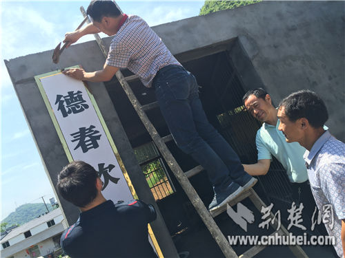 工作人员帮助张德春挂上工厂招牌